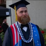 A bearded young man in full regalia wearing the Veteran's stole.