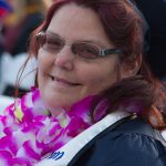 A woman with red hair and glasses smiling at commencement.