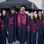 A group of smiling graduates in cap and gown.