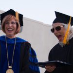 Dr. Schilling and a woman receiving her degree, laughing at commencement.
