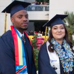 Male and female graduates smiling at commencement.
