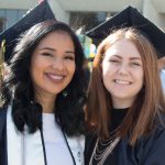 Two smiling young women in their graduation caps during commencement.