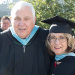 A man and a woman smiling in their academic regalia.