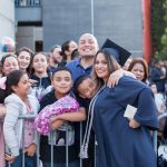 A female graduate in full regalia posing with family.