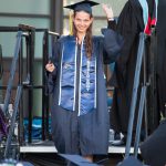 A graduate waves as she prepares to receive her degree during commencement.