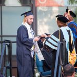 A graduate being congratulated while receiving his degree during commencement,