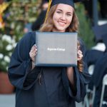 Smiling graduate holding degree.