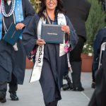 Smiling graduate holding degree.