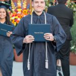 Happy graduate smiling and holding his degree.