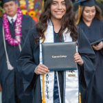 Smiling graduate holding degree.