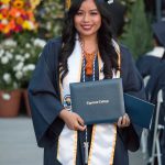 Smiling graduate holding degree.