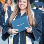 Smiling graduate holding degree.