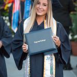 Smiling graduate holding degree.