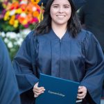 Smiling graduate holding degree.