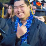 Happy graduate smiling and holding up fingers.