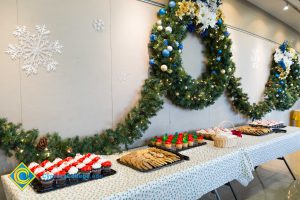 Dessert table with large wreaths and garland hanging on the wall with snowflake designs.