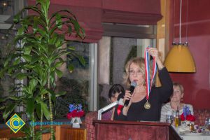 Gail Taylor with a microphone in one hand and holding up a medal in another .