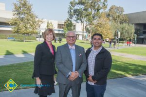 Dr. JoAnna Schilling in a black suit and pink blouse, Juan Garcia in a checkered shirt and black jacket and a man wearing glasses and a grey suit with blue shirt and light colored bowtie.