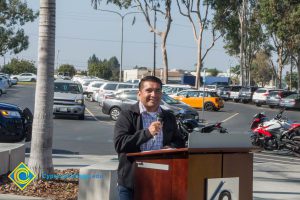 VRC Director, Juan Garcia smiling at the podium with a microphone in his hand.