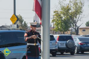 A U.S. Marine in full Dress Blue uniform raising the flag.