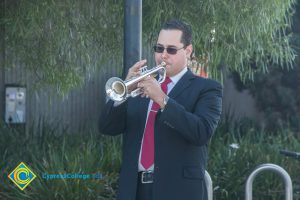 A man in a black suit and red tie playing the trumpet.