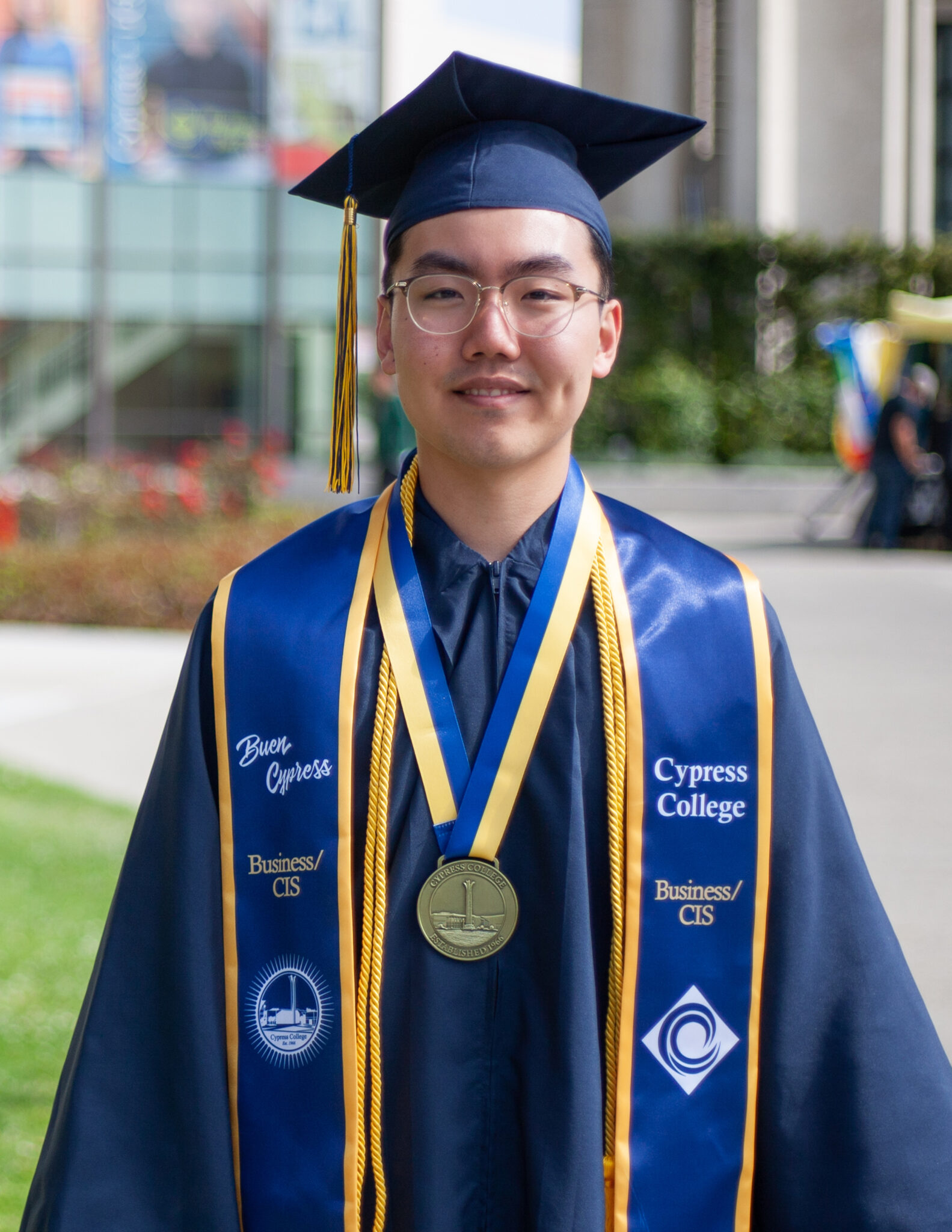 Portrait of Jesse Chang, the 2023 Presidential Scholar of Distinction for the Business/CIS pathway, wearing regalia with Gateway Plaza in the background