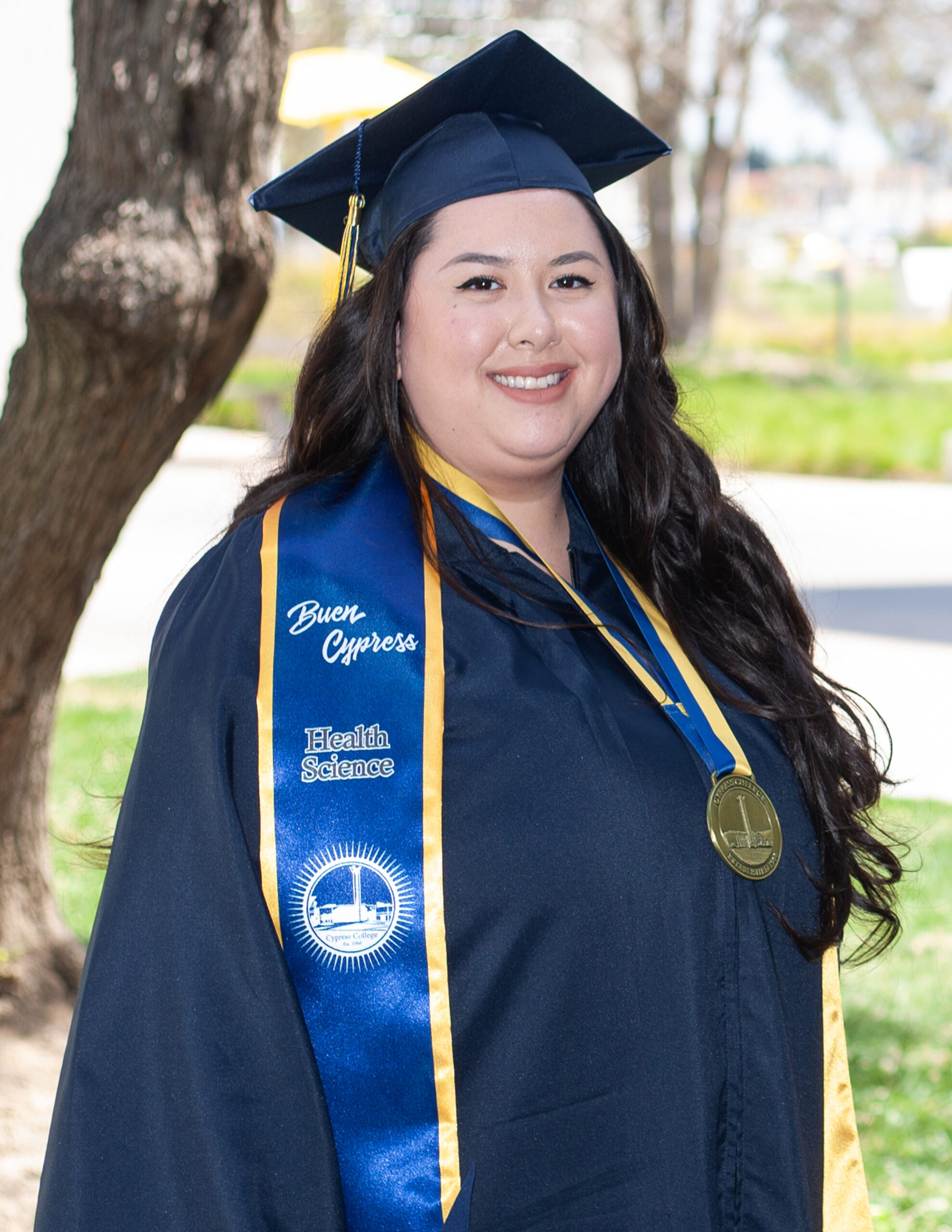 Portrait of Stephanie Wood, the 2023 Presidential Scholar of Distinction for the Health Science pathway, wearing regalia with the pond in the background.