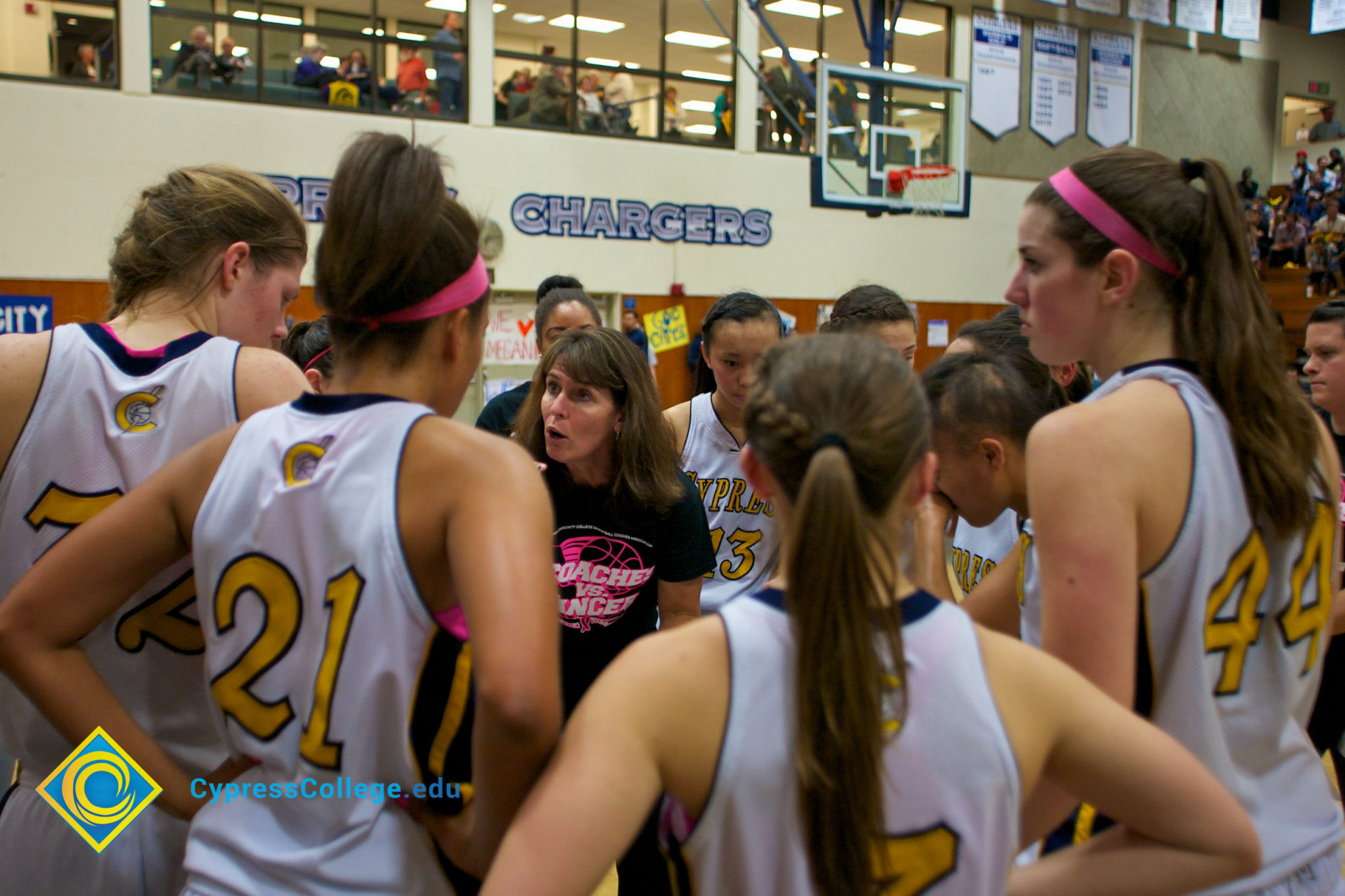 Women's basketball team huddled while their coach gives direction.