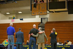 Former Cypress College basketball players stand and watch as a jersey is retired.