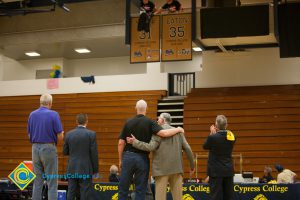Former Cypress College basketball players stand and watch as a jersey is retired.