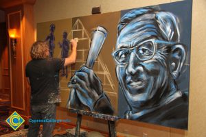 Artist painting a large mural of John Wooden.