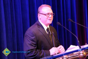 Man in a suit and tie standing at the microphone.