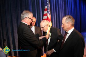 President Bob Simpson placing an award on an older gentleman as two other men in suits look on.