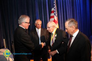 President Bob Simpson placing an award on an older gentleman as two other men in suits look on.