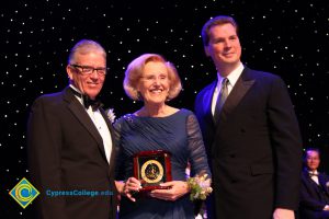 President Bob Simpson with a man in a black suit and tie and a woman in a navy blue dress holding an award.