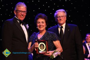 President Bob Simpson with a man in a black suit and tie and a woman in a black dress holding an award.