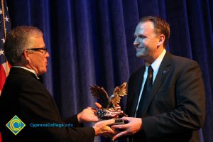 President Bob Simpson handing a man in a suit an award.