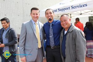 A young man with a goatee in a blue shirt and tie with Rick Rams and Paul de Dios.