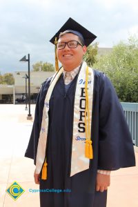 A student smiles in his cap and gown during the 48th Commencement.