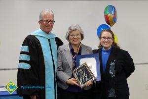 President Bob Simpson and Jolena Grande with a woman with grey hair, glasses, grey jacket and blue blouse holding award and certificate.