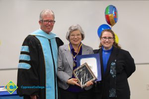 President Bob Simpson and Jolena Grande with a woman with grey hair, glasses, grey jacket and blue blouse holding award and certificate.