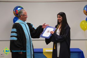 President Bob Simpson with a young lady in her graduation gown holding a certificate.