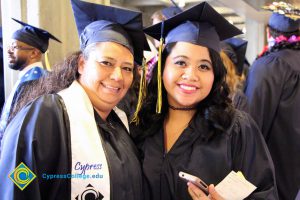 Two women in graduation cap and gown smiling.