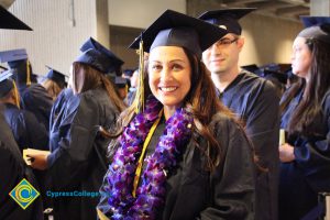 A young lady in graduation cap and gown smiling during the 48th Commencement.