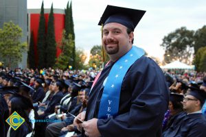 A student smiles in his cap and gown during the 48th Commencement.