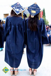 Two young ladies with cap and gown showing off their decorated caps.