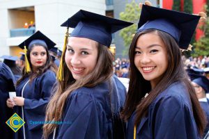 Three young ladies smiling in their cap and gown.