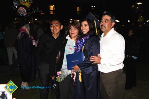 A young woman in her cap and gown smiling with her family.