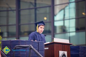 A young man in cap and gown speaking during the 48th Commencement.