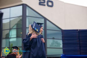 Two students in cap and gown embracing during the 48th Commencement.